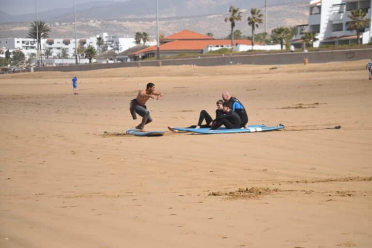 średniozaawansowani surferzy mają lekcje surfingu, aby nauczyć się prawidłowych technik surfowania i odczytywania fal na plaży w Agadirze